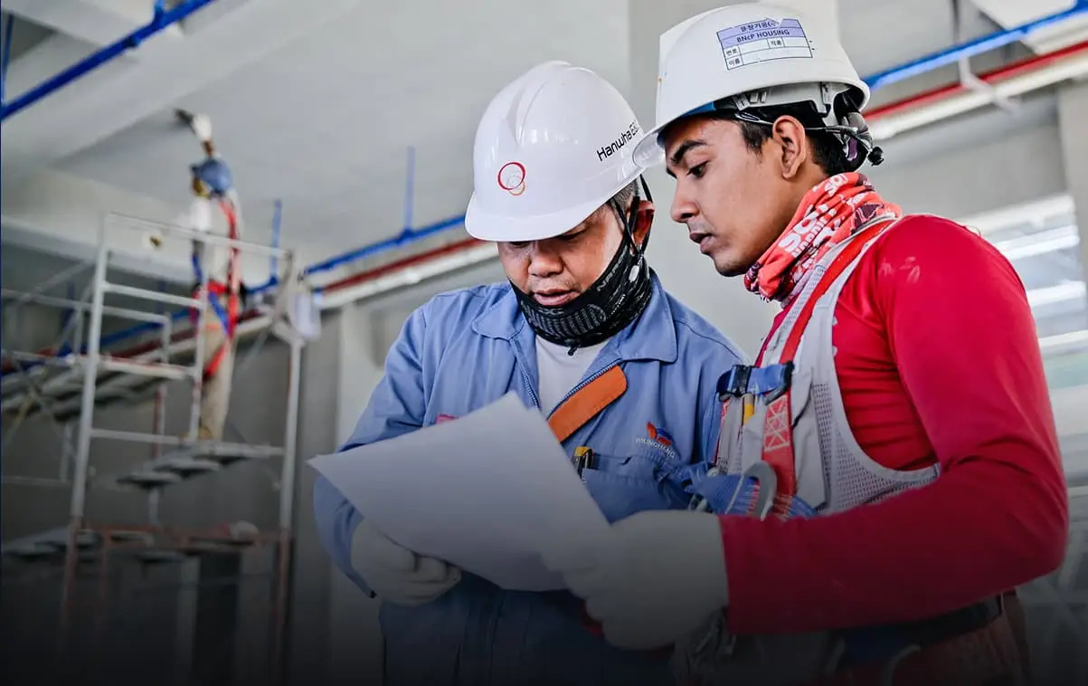 Construction workers discussing a document on-site, symbolizing workers' compensation claims process