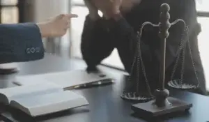 Business and lawyers discussing contract papers on office desk with brass scale.