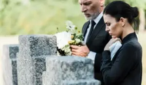 Two people grieving on a tombstone.