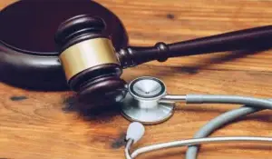 A gavel and stethoscope are beside each other.