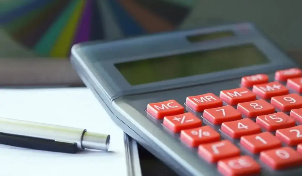 Calculator and pen on desk, illustrating the process of filing a car insurance claim in Illinois