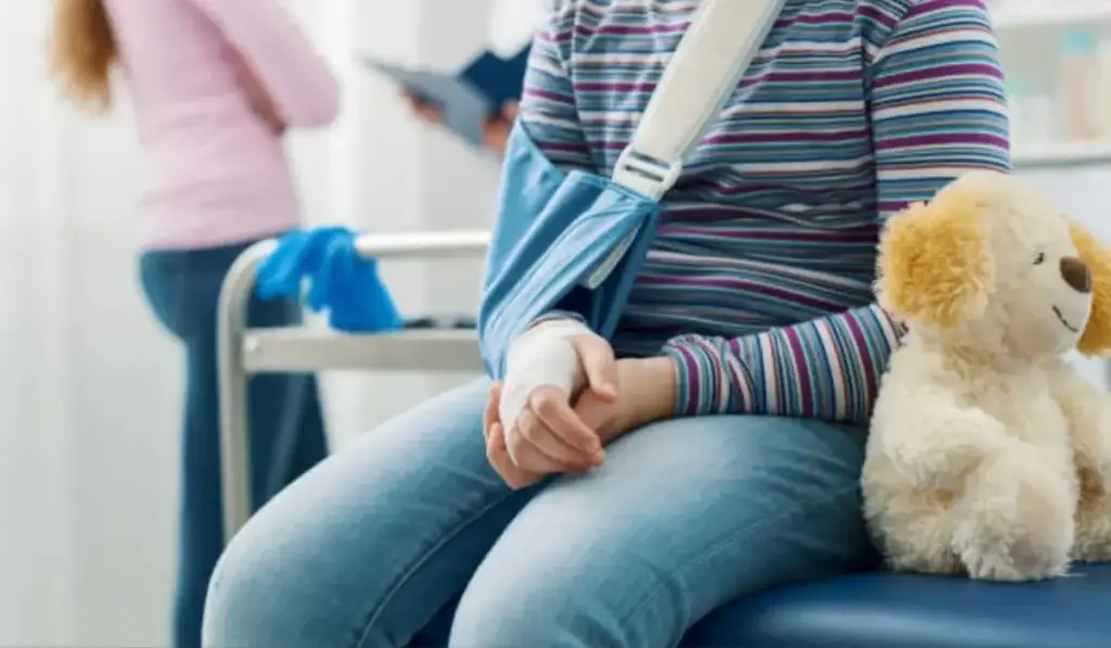 Child with arm injury sitting in a clinic, representing child injury cases and legal guidance in Chicago.