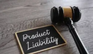 Gavel next to a chalkboard with "Product Liability" written on it, representing defective products.